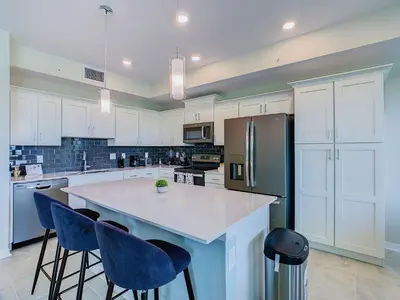 a kitchen with a large island with blue bar chairs at Cute Lakeview 2BR Condo with 2 Clubhouses in Kissimmee