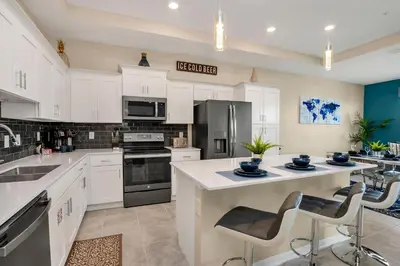 a kitchen with white cabinets and a large island with bar stools at Cozy Condo Near Disney wPool View FREE WaterPark in Kissimmee