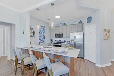 a kitchen with a large white island with chairs at Top floor condo with view of lake, pool and fireworks! Next to Convention Center! in Orlando