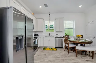 a kitchen with white cabinets and a table and chairs at Margaritaville Cottage, PRIVATE POOL, Near Disney in Orlando