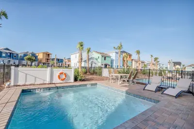 a swimming pool with chairs and a table and houses at Margaritaville Cottage, PRIVATE POOL, Near Disney in Orlando