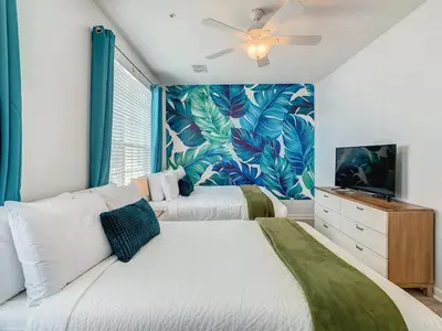 a bedroom with two beds with a tropical wallpaper at Stylish Vista Cay Townhome Near Conv. Ctr I-Dr. in Orlando