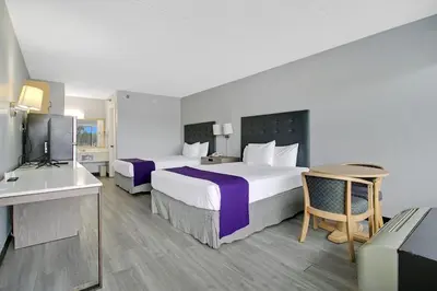 a hotel room with two beds and a television at Home 1 Suites Extended Stay - Kissimmee in Kissimmee