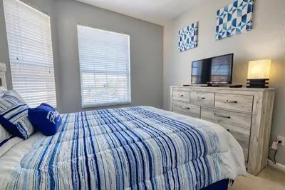 a bedroom with a bed with a television and a dresser at Windsor Hills Resort 3 Bedroom Condo 5 Minutes to Disney in Orlando