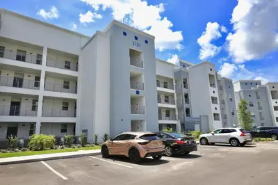 a large white building with cars parked in a parking lot at Great apartment in Storey Lake resort with great amenities next to Disney! in Kissimmee