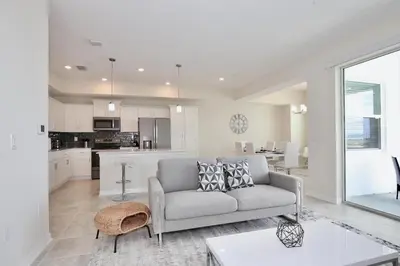 a living room with a couch and a kitchen at Great apartment in Storey Lake resort with great amenities next to Disney! in Kissimmee