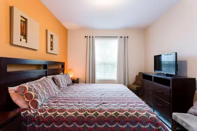 a bedroom with a bed and a flat screen tv at Spacious 2BR 2BA with Balcony 5 Mins to Convention Center & Epic Universe in Orlando