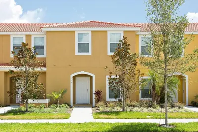 a yellow house with trees in front of it at 3Br 3Bath Townhome BBQ Pool 15min Disney 1291ft in Kissimmee