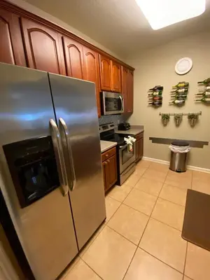 a kitchen with a stainless steel refrigerator and wooden cabinets at 3Br 2Bath Condo Balcony 5min Conv Center 1388ft in Orlando