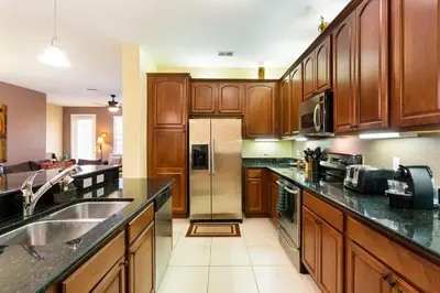 a kitchen with wooden cabinets and a stainless steel refrigerator at 3Br 2Bath Condo Balcony 5min Conv Center 2087ft in Orlando