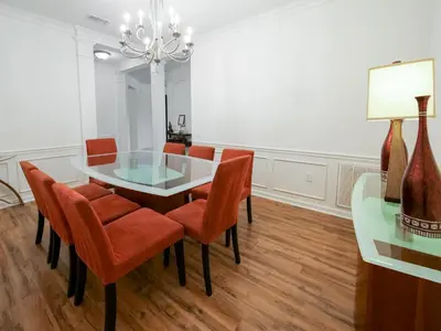 a dining room with a glass table and orange chairs at 4Br 2Bath Condo Balcony 5min Conv Center 2020ft in Orlando