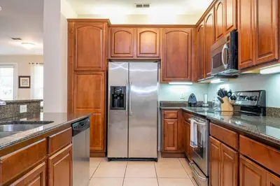 a kitchen with wooden cabinets and a stainless steel refrigerator at Renovated 4Br Condo 5min Conv Center in Orlando