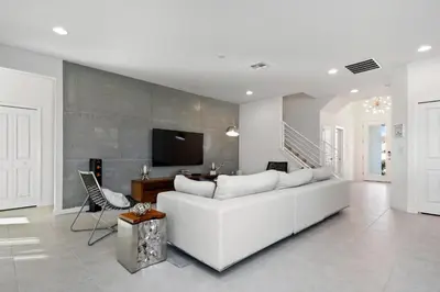 a white living room with a white couch and a tv at 5Br 5Bath Pvt Home BBQ Pool 15min Disney 3056ft in Kissimmee
