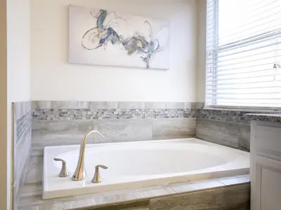 a white bath tub in a bathroom with a painting at 5Br 5Bath Pvt Home BBQ Pool 10min Disney 3077ft in Kissimmee