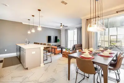 a kitchen and living room with a table and chairs at 4 Bed Storey Lake Resort With Lazy River townhouse in Kissimmee
