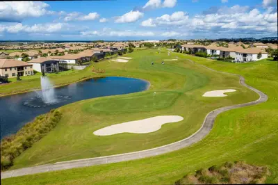 an aerial view of a golf course with a pond at Gorgeous 4 Bd w/ Pool at Champions Gate Resort 1020 in Orlando