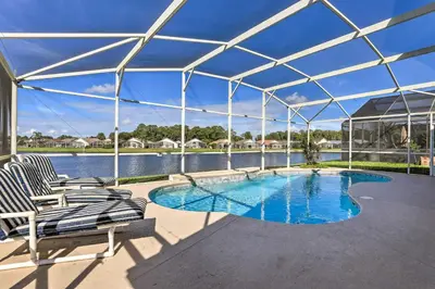 a swimming pool in a tent with chairs and water at 8 Mi to Disney World Home with Lanai and Game Room! in Kissimmee