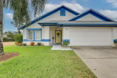 a white and blue house with a garage at 7 Mi to Disney Family-Friendly Home with Pool! in Kissimmee