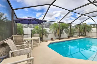 a patio with a pool and a table and an umbrella at 7 Mi to Disney Family-Friendly Home with Pool! in Kissimmee