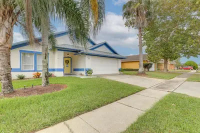 a house with palm trees in front of it at 7 Mi to Disney Family-Friendly Home with Pool! in Kissimmee