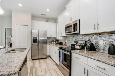 a kitchen with white cabinets and a stainless steel refrigerator at Magical Memories Await at Jimmy Cricket's Retreat in Kissimmee