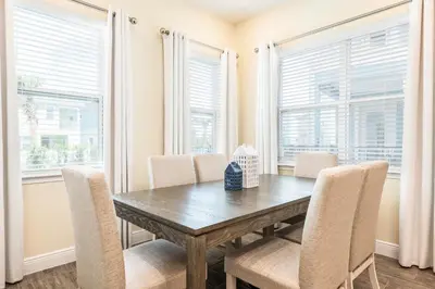 a dining room with a wooden table and chairs and windows at Comfy Cottage Near Disney With Margaritaville Resort & Island H20 Waterpark Access - 2926Sr in Orlando