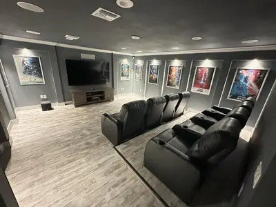 a living room with black leather furniture and a flat screen tv at Mickeys Palm - Brand New! 6BR Modern with Private Pool Hot Tub BBQ Home Theater - 2 Miles to Disney in Orlando