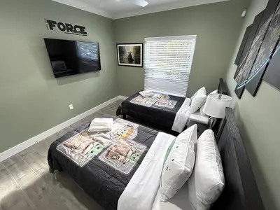 a bedroom with two beds and a tv in it at Mickeys Palm - Brand New! 6BR Modern with Private Pool Hot Tub BBQ Home Theater - 2 Miles to Disney in Orlando