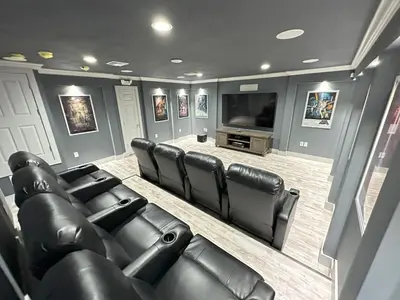 a movie room with leather chairs and a flat screen tv at Mickeys Palm - Brand New! 6BR Modern with Private Pool Hot Tub BBQ Home Theater - 2 Miles to Disney in Orlando