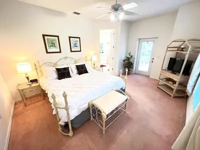 a bedroom with a large bed and a television at Mickeys Homestead - Stylish 4BR Lakefront Cottage with Huge South Facing Pool Hot Tub BBQ - 2 miles Disney! in Orlando