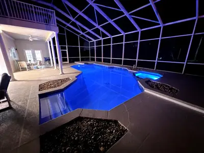 a large swimming pool with blue water in a building at Mickeys Homestead - Stylish 4BR Lakefront Cottage with Huge South Facing Pool Hot Tub BBQ - 2 miles Disney! in Orlando