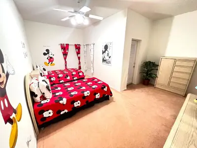 a bedroom with a bed with mickey mouse bedding at Mickeys Homestead - Stylish 4BR Lakefront Cottage with Huge South Facing Pool Hot Tub BBQ - 2 miles Disney! in Orlando
