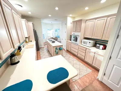 a kitchen with wooden cabinets and a white counter top at Mickeys Homestead - Stylish 4BR Lakefront Cottage with Huge South Facing Pool Hot Tub BBQ - 2 miles Disney! in Orlando