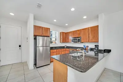 a kitchen with wooden cabinets and a stainless steel refrigerator at Regal Oaks Resort Townhouse in Kissimmee