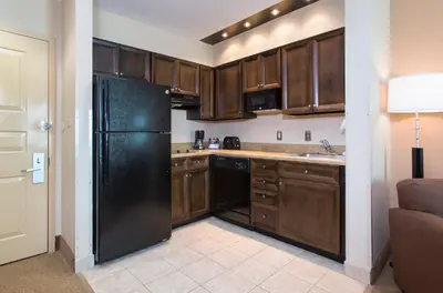 a kitchen with wooden cabinets and a black refrigerator at Hawthorn Extended Stay by Wyndham Orlando in Orlando
