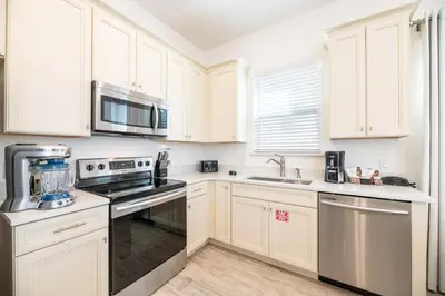 a kitchen with white cabinets and stainless steel appliances at Delightful Cottage Near Disney With Margaritaville Resort & Island H20 Waterpark Access - 2956Sr in Orlando