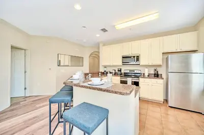 a kitchen with a large island with two blue bar stools at Spacious 3BR Condo with Pool, near Disney! in Orlando