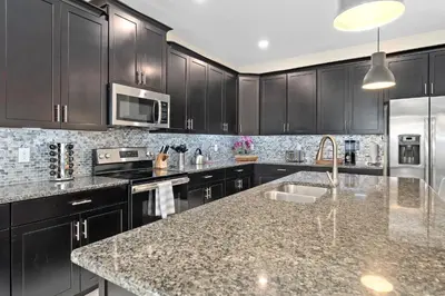 a kitchen with black cabinets and a granite counter top at Storey Lake -6 Bedrooms Luxury home w-pool & spa in Kissimmee