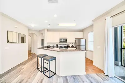 a kitchen with white cabinets and a counter with stools at Upstay Condo with Outdoor Pool & Sauna in Orlando