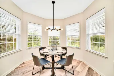 a dining room with a table and chairs and windows at Upstay Condo with Outdoor Pool & Sauna in Orlando