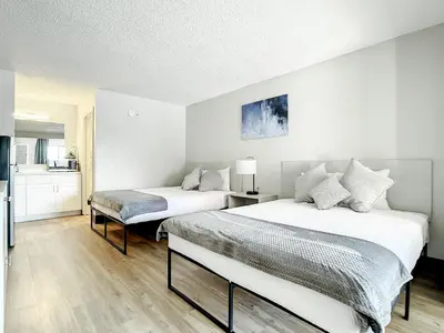 a bedroom with two beds and a kitchen at Stayable Kissimmee West in Kissimmee