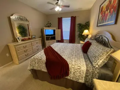 a bedroom with a bed and a dresser and a television at 3 bedroom Disney Condo Windsor Hills in Orlando
