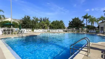 a large blue swimming pool with chairs and umbrellas at Resort 5 Bed Private Pool & Spa, Game Room Home villa in Kissimmee