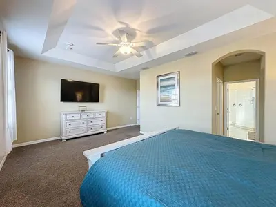a bedroom with a blue bed and a flat screen tv at Veranda Home, 8br, 6 en-suites, Lake View,POOL SPA villa in Kissimmee
