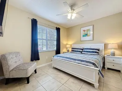 a bedroom with a bed and a chair and a window at Veranda Home, 8br, 6 en-suites, Lake View,POOL SPA villa in Kissimmee
