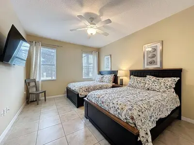 a bedroom with two beds and a ceiling fan at Veranda Home, 8br, 6 en-suites, Lake View,POOL SPA villa in Kissimmee