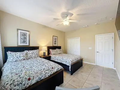 a bedroom with two beds and a ceiling fan at Veranda Home, 8br, 6 en-suites, Lake View,POOL SPA villa in Kissimmee