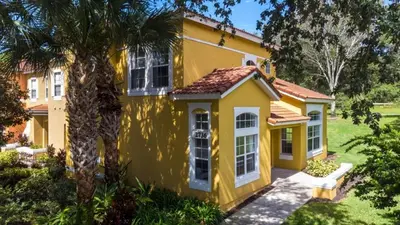 a yellow house with a palm tree in front of it at Disney Area 4 bed 3,5 Bathroom Emerald Island townhouse in Kissimmee