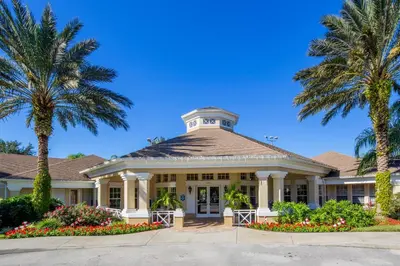 a building with palm trees and flowers on a street at The Great Escape - A spacious 1st floor condo on Windsor Palms Resort - close to Disney in Kissimmee