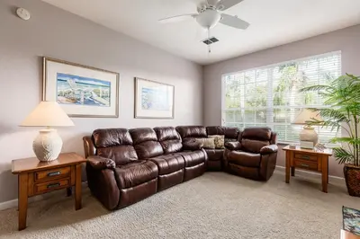 a living room with a leather couch and a window at The Great Escape - A spacious 1st floor condo on Windsor Palms Resort - close to Disney in Kissimmee